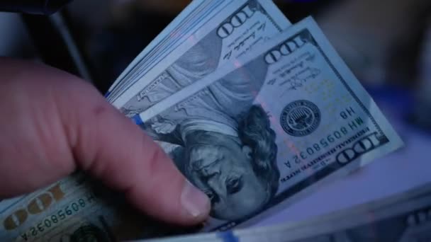Billetes de dólar en la luz ultravioleta. Concepto - chequeando dólares por autenticidad. Búsqueda de marcas de agua en billetes. — Vídeo de stock