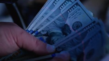 Ultraviyole lambayla 100 dolarlık banknotları kontrol ediyorum. Dolandırıcılık suçu.