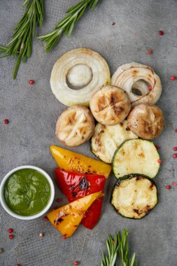 Beton bir arka planda kurutulmuş bitkilerle ızgara sebze ve mantar..