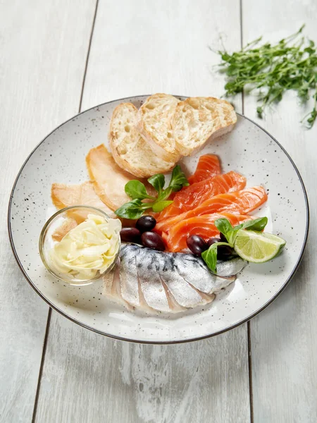 Fish plate with different types of salted fish on a wooden background