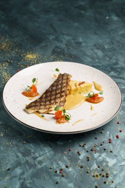 Beyaz tabakta ızgara, fırında pollock veya kömür balığı filetosu ve yeşil arka plan.