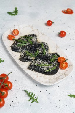 Kırmızı somon havyarıyla doldurulmuş siyah gözleme. Hamur boyalı mürekkep balığı.