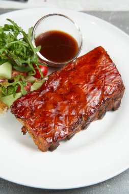 Barbekü soslu ızgara domuz pirzolası ve balda karamelize edilmiş. Koyu beton arkaplanı dosyalamak için beton bir tahtada biraya lezzetli atıştırmalıklar..