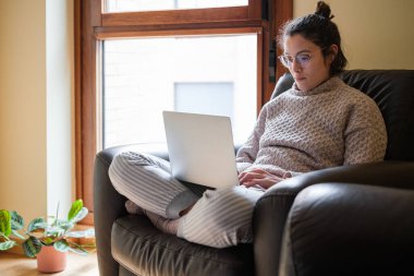 Kanepede dizüstü bilgisayarla çalışan bir kadın..