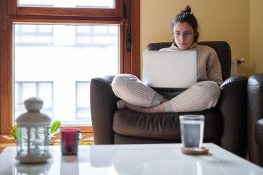 Evde pijamalı bir kadın çalışıyor..