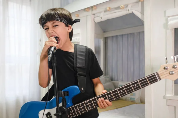 Young rocker child with a bandana singing at the microphone at home.