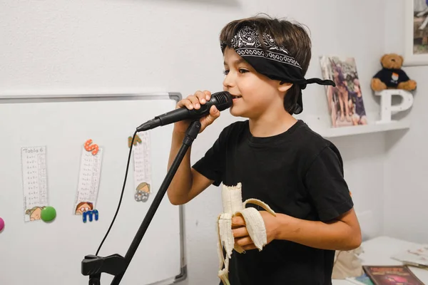Young child with a banana giving a rock concert at home.