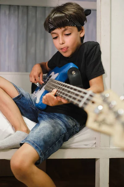 Young child playing the bass at home. Vertical photo.