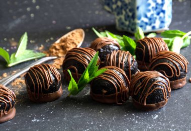 Koyu arkaplanda nane yaprakları olan çikolata topu şekerleri. 