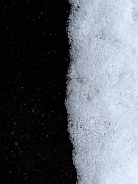 Granica czerni i bieli. Krawędź śniegu na czarnym betonie — Zdjęcie stockowe