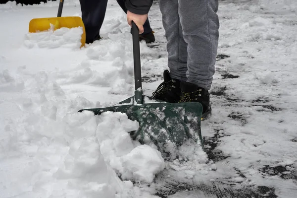 Man med snöskyffel rengör uppfarten på vintern. Vintertid — Stockfoto