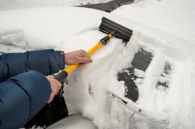 Aletle insan kolları. Kışın kar yağarken arabasındaki karları temizleyen adam. Yüksek kalite fotoğraf