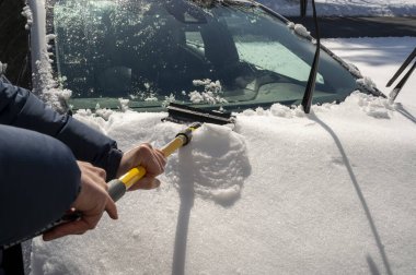 Adam kışın kar fırtınasından sonra arabasını kardan temizliyor. Kar fırtınası ve yoğun kar. Yüksek kalite fotoğraf