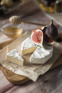 İncirli peynirli Camembert peyniri, tatlım. Yuvarlak brie peyniri ya da tahta beyazı ile meyve dilimi üzerine camambert peyniri. Seçici odak