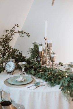 decorated New Year's table in light. New Year's festive table setting. Merry Christmas family dinner by candlelight. Gold. Beautiful table setting for Christmas dinner