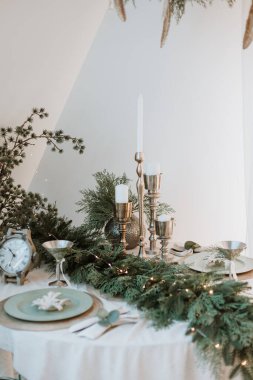 decorated New Year's table in light. New Year's festive table setting. Merry Christmas family dinner by candlelight. Gold. Beautiful table setting for Christmas dinner