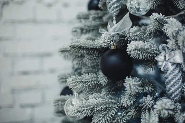 黒と銀のおもちゃと背景に輝く明るいライトと伝統的な人工クリスマスツリー — ストック写真
