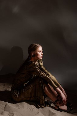 Kumlu fotoğraf stüdyosu odası. yaratıcı moda fotoshoot. Uzun bronz elbiseler içinde güzel bir model..
