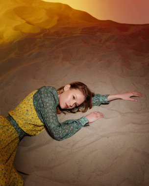 Kum stüdyosunun renkli ışığı üzerinde parlak elbiseli genç ve güzel bir manken. Sevgi dolu toprak kavramı