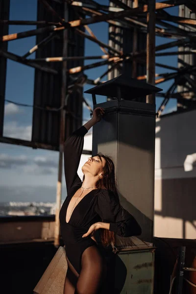 Portrait of a handsome courageous woman in black clothes and silver boots posing on a metal industrial staircase. Urban grunge style. Female fashion.