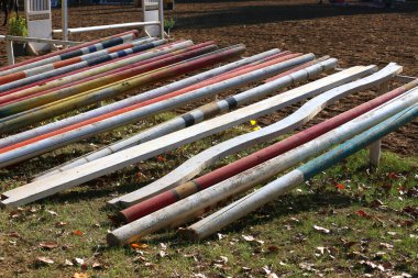 Atlamak için zeminde eski ahşap bariyerler var. Gün batımında kırsal bir pistte sıralanmış engelleri göster