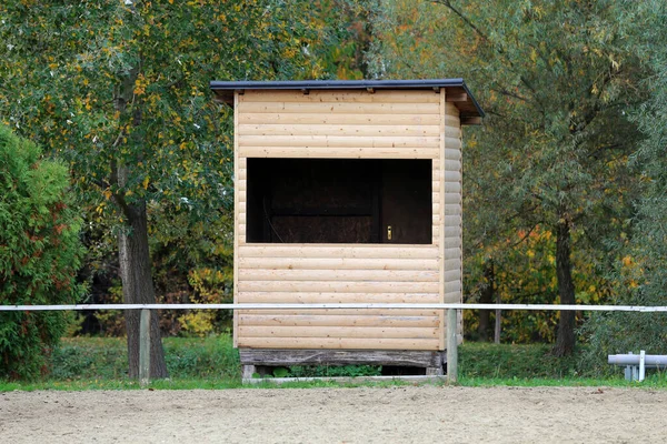 Photo of a sand covered equestrian horse arena with wooden house for judges outdoors summertime