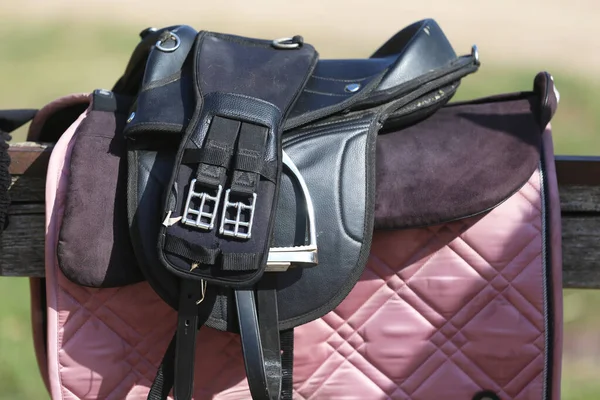 Close up of a sport horse saddle. Quality classical leather saddle ready for horse workout. Equestrian sport background outdoors