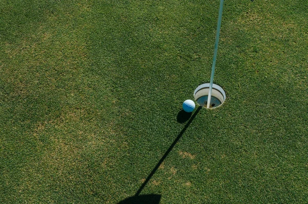 Yeşil çimlerin üzerinde golf deliği ve top