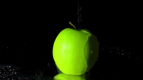 Zeitlupe Spritzt Wasser Auf Den Apfel Auf Schwarzem Hintergrund — Stockvideo