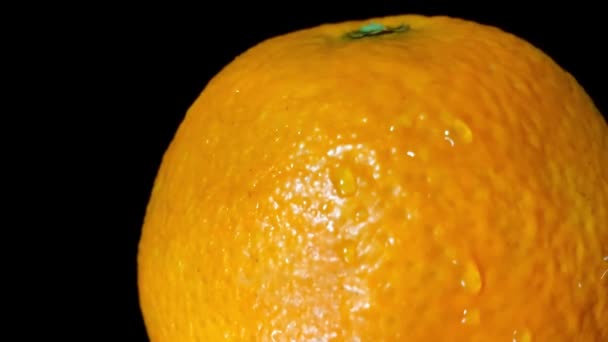 A vízcseppekről készült stúdiófelvétel a narancs gyümölcsre esik. Fekete háttér. 4K videofelvétel — Stock videók