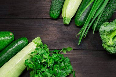 Koyu ahşap arka planda yemek pişirmek için organik yeşil sebzeler ve şifalı bitkiler. Üst Manzara. Sağlıklı, vejetaryen, diyet yemeği kavramı.