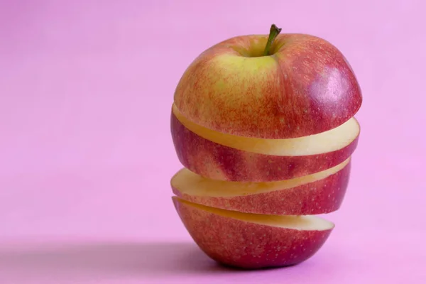 ピンクの背景に熟したリンゴを浮遊させます ビタミン 健康的な食事の概念 最小限の果物のアイデア スライスしたリンゴが空中に浮かんでいます 空飛ぶ果物と創造的なコンセプト — ストック写真