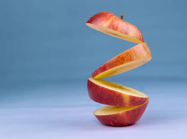 青い背景に熟したリンゴを浮遊させます ビタミン 健康的な食事の概念 最小限の果物のアイデア スライスしたリンゴが空中に浮かんでいます 空飛ぶ果物と創造的なコンセプト — ストック写真