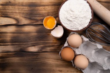 Pişirme malzemeleri: un, yumurta, ahşap zemin üzerinde yumurta sarısı. Düz yatıyordu. Üst görünüm.