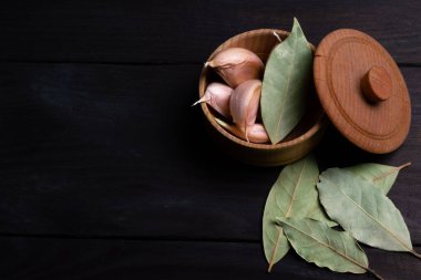 Koyu ahşap dokusunda koyu yapraklı sarımsak karanfilleri. Mesaj için yer var. Üst görünüm