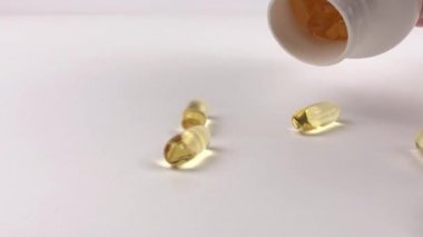 Beyaz yüzeyinde balık yağı olan Omega 3 sarı hapları. Doğal tıp konsepti