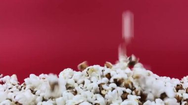 Patlamış mısır kırmızı arka planda ağır çekimde bir yığın üzerine düşüyor