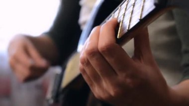 Genç bir kadın gitar çalıyor. Kız evde kalırken gitar çalışıyor.