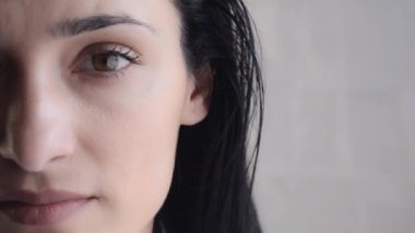 Genç Esmer Kadın 'ın yakın plan portresi. Yarım Surat. Güzel kız gözlerini aç ve kameraya bak.