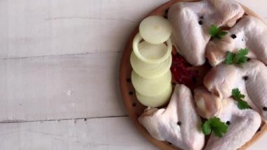 Tahtada taze çiğ tavuk kanatları ve malzemeler.