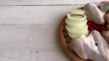 Tahtada taze çiğ tavuk kanatları ve malzemeler.