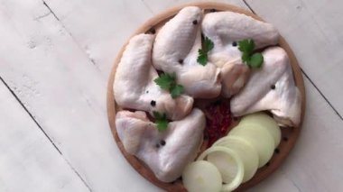 Tahtada taze çiğ tavuk kanatları ve malzemeler. Döndürme hareketi. Beyaz tahta arkaplan