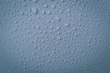 Gri arkaplana düşen yağmur damlaları kavramı soyut ıslak gri yüzey ve yüzeyinde kabarcıklar var.