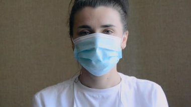 Ofiste tıbbi maske takan güzel bir kadın doktorun portresi. Tıp, insanlar ve bulaşıcı hastalıklar kavramı.