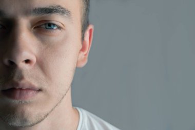 Mavi gözlü, yarım yüzlü, güzel bir gencin portresi.