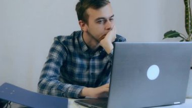Uzaktan kumandalı bir iş yerinde dizüstü bilgisayarla oturan düşünceli bir iş adamı. Ofiste düşünceli profesyonel düşünce. Etrafa bakan odaklanmış iş adamı suratı. Ciddi erkek portresi.