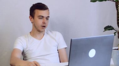 Genç iş adamı ofiste video konferansında konuşuyor. Ev bilgisayarında video görüşmesi yapan yakışıklı bir işçi. Uzak iş yerlerinde jestleri olan erkek profesyonel açıklama projesi