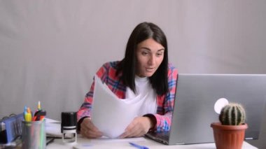 Heyecanlı genç bayan kazananın başarılı bir iş anlaşması var. Bilgisayara bakıyor ve online başarıyı kutluyor. Öforik kadın yeni bir iş fırsatı yakalıyor, e-postada iyi haberler okuyor, zafere seviniyor, motive oluyor. Kağıt dökümanları atıyor.