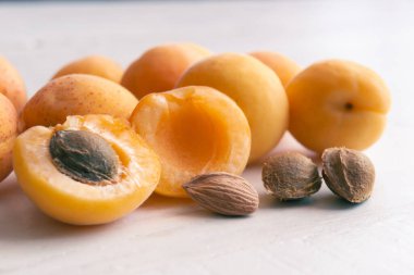 Beyaz ahşap arka planda kayısılar ve çekirdekler. Kayısı tohumları.