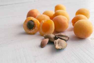 Beyaz ahşap arka planda kayısılar ve çekirdekler. Kayısı tohumları.